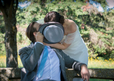 photo mariage couple s'embrassent derrière un chapeau